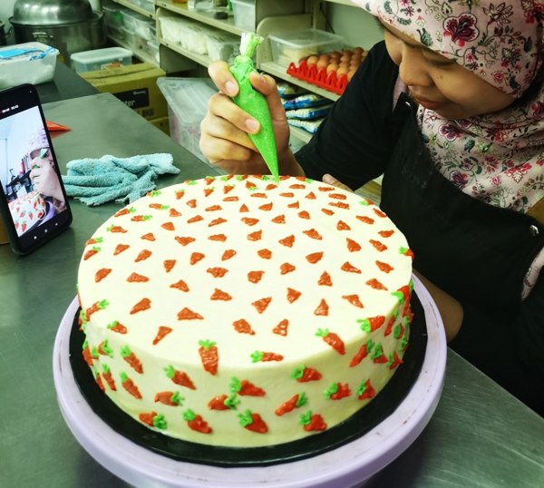 Piping a carrot cake by hand in the Indah kitchen